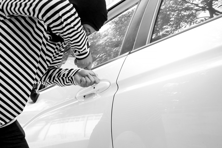Black and white image of the man robber with a balaclava on his head trying to break into the car/Selective focus/Criminal and car thief concept